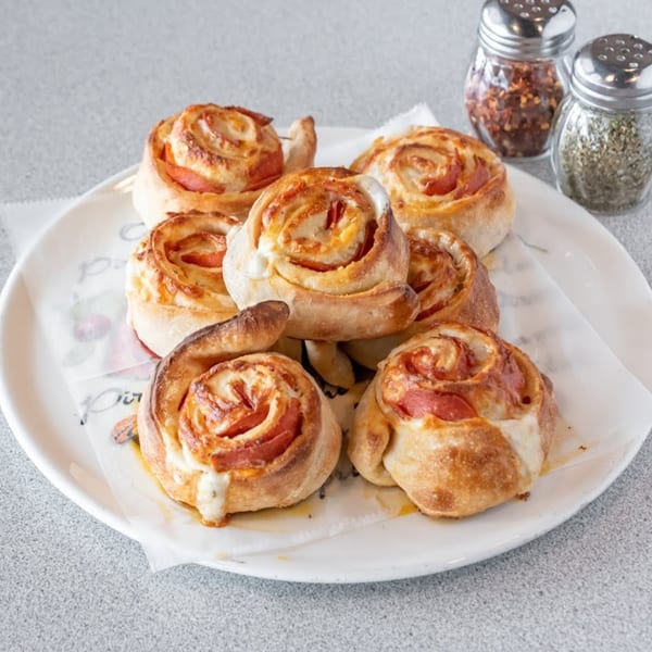 A plate of Soprano's Pizzeria & Restaurant's pepperoni and cheese pinwheels, with shakers of spices.